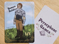Illustrated human soldier token card featuring woman soldier in light armor standing in a field with  her hair  in a crown braid.