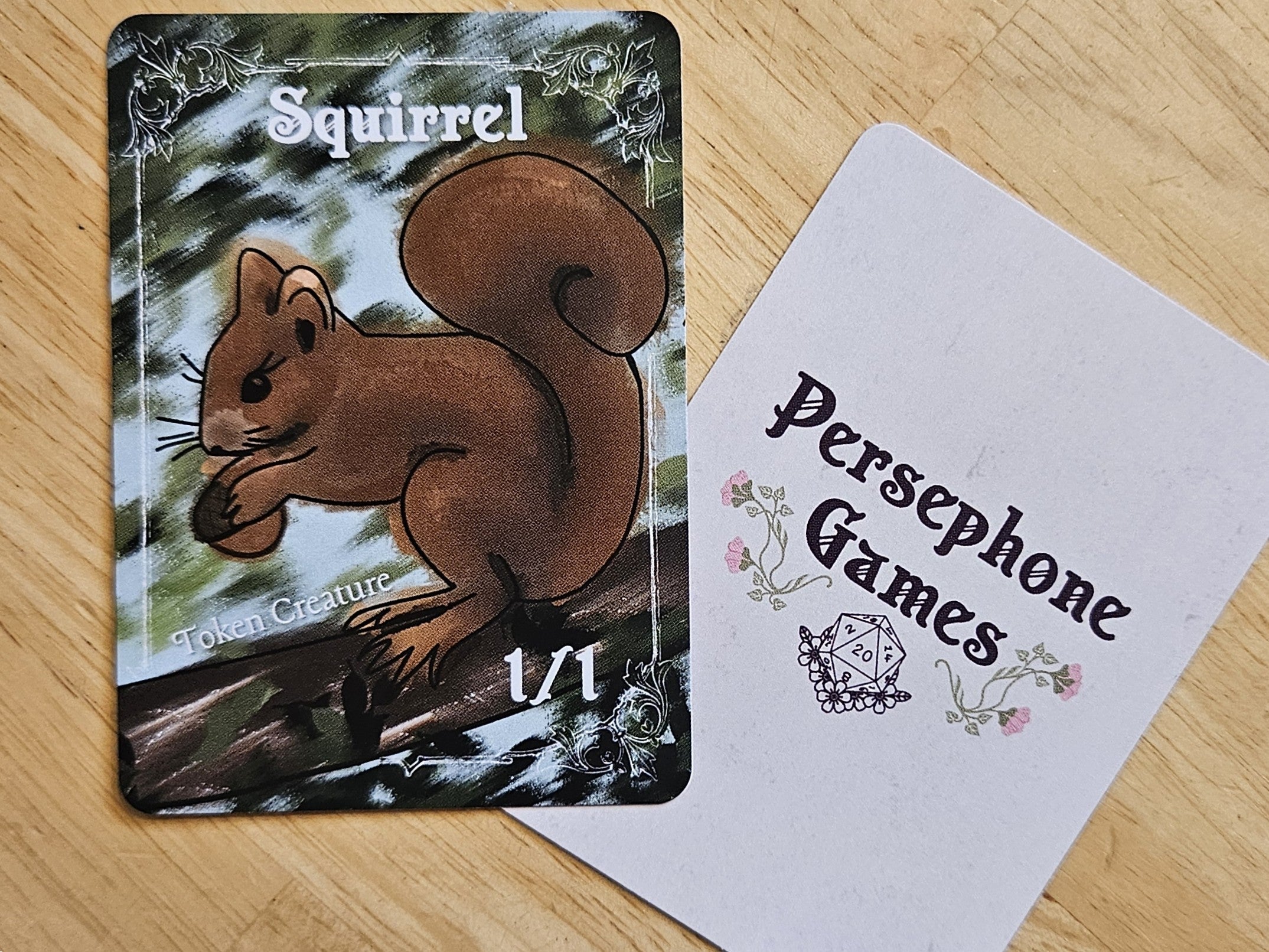 Illustrated 1/1 Squirrel token card featuring brown squirrel holding an acorn sitting on a tree branch